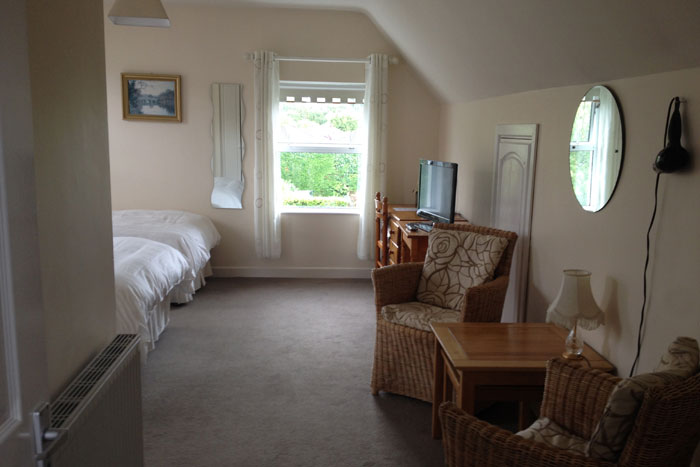A twin bedroom at Avondale B&B with two single beds, wicker chairs and a seating area by the window.